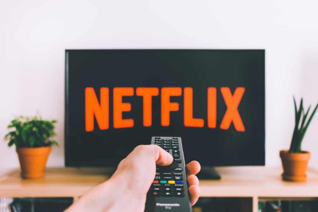 A hand holding a remote to watch Netflix on TV
